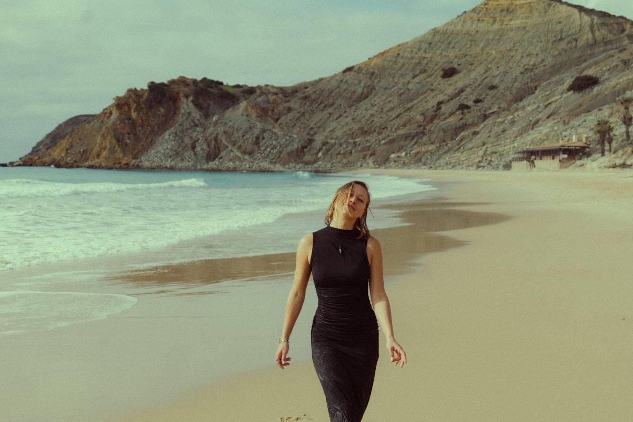 Maaike walking on a sandy beach toward the camera