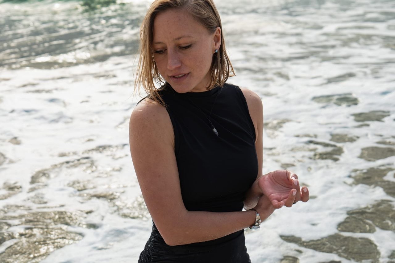 Maaike standing in the surf along a rocky coastline